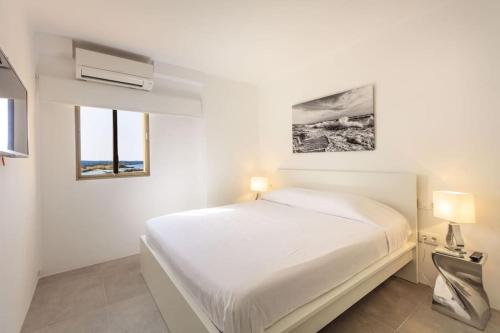 a white bedroom with a bed and two windows at La Savina Dream in La Savina