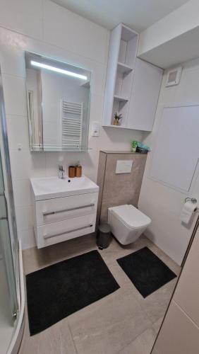 a white bathroom with a sink and a toilet at Lesíček in Vysoké Tatry