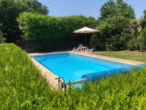 une piscine avec un parasol, une table et des chaises dans l'établissement Jasmin Cottage with seasonal Swimming Pool, à Le Mesnil-Gilbert