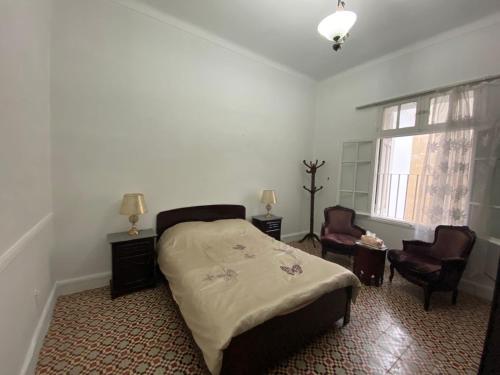 a bedroom with a bed and two chairs and a window at Chez khaleed in Rabat