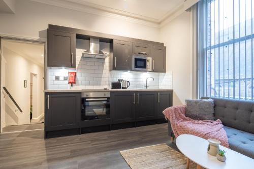 a kitchen with black cabinets and a couch in a living room at MARSH lux 3 in Manchester