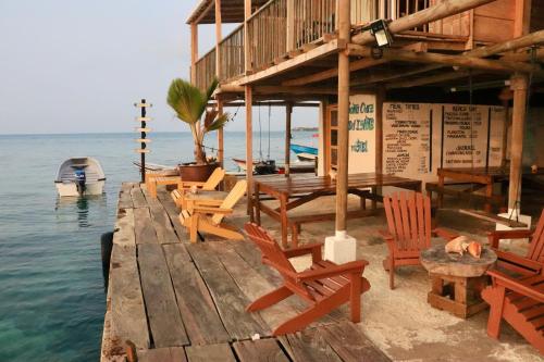 a dock with chairs and a house on the water at Hostel Santa Cruz del Islote in Santa Cruz del Islote