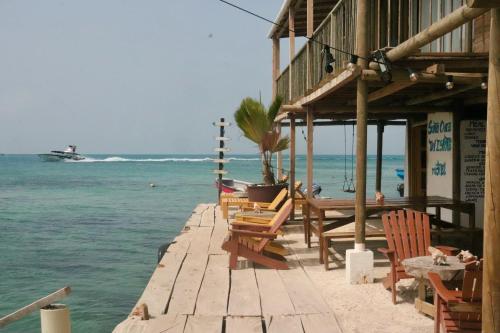 a dock with chairs and a table and a boat in the water at Hostel Santa Cruz del Islote in Santa Cruz del Islote