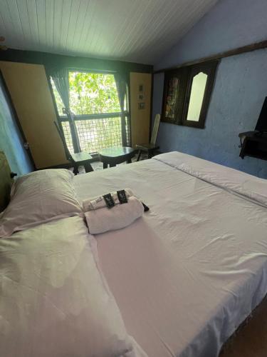 Cette chambre comprend un grand lit blanc et une fenêtre. dans l'établissement Pousada Lua Bonita, à Nova Lima