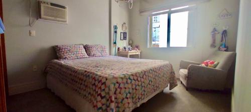 a bedroom with a bed and a chair and a window at Apartamento com localização fantástica na praia de Balneário Camboriú in Balneário Camboriú
