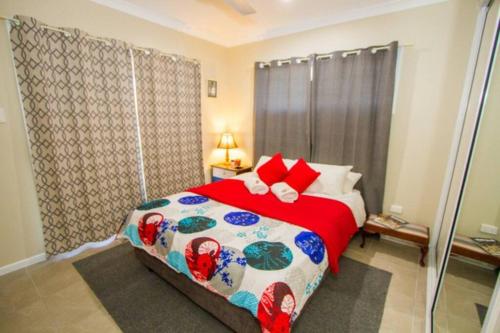 a bedroom with a large bed with red pillows at Seas The Day - Pet-friendly house in Agnes Water in Agnes Water