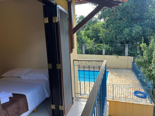a balcony with a bed and a swimming pool at Pousada dos Girassóis in Conservatória