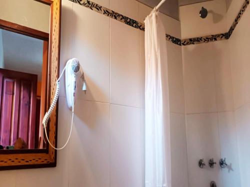 a bathroom with a shower with a blow dryer on the wall at Ipay Alojamiento Familiar in Purmamarca