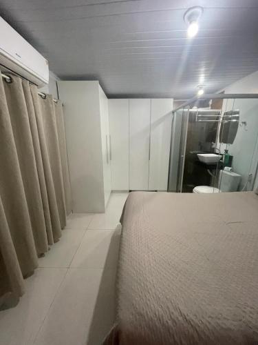 a bedroom with a bed and a bathroom with a sink at Apartamento Mobiliado centro de Palmas in Palmas
