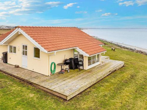 ein kleines Haus auf einer Holzterrasse neben dem Wasser in der Unterkunft 4 person holiday home in Vinderup in Vinderup