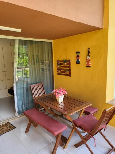 a wooden table and chairs in a room with a yellow wall at Gravatá Winterville Residence in Gravatá