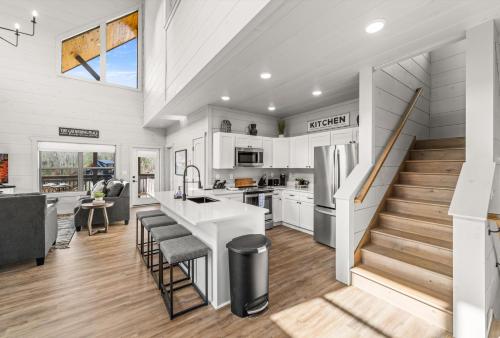 a kitchen and living room with a staircase and a house at NEW Cabin - Heated Indoor Pool, Jacuzzi, Gameroom in Pigeon Forge