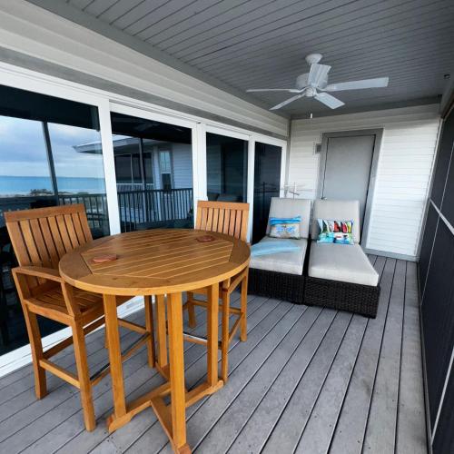 una mesa de madera y sillas en una terraza con sofá en Beach Villa One Bedroom A3124A villa, en Cape Haze