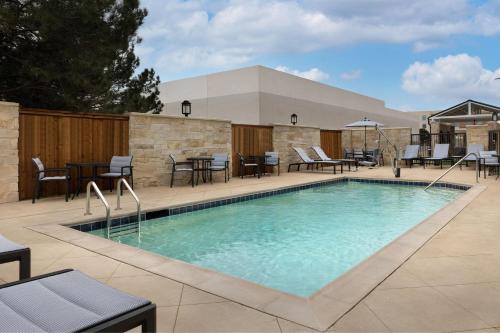 a swimming pool with chairs and tables on a patio at TownePlace Suites by Marriott Abilene Southwest in Abilene