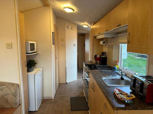 a small kitchen with a sink and a microwave at BelLa VistA - Holiday Home On The Beach in Clacton-on-Sea