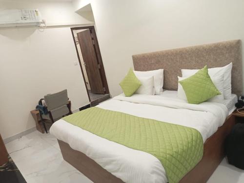 um quarto com uma cama grande e almofadas verdes e brancas em Hotel Fortune Residency em Nova Deli