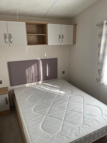 a large bed in a room with white cabinets at Gold star 6 birth caravan in Berrow