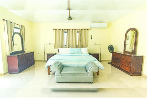 una camera con letto, sedia e specchio di "Villa Infinito"Bani's Exclusive Beachside Mansion a La Noria