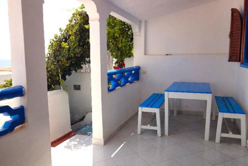 a table and two blue benches on a patio at Appart Hôtel La Planque in Oued Laou
