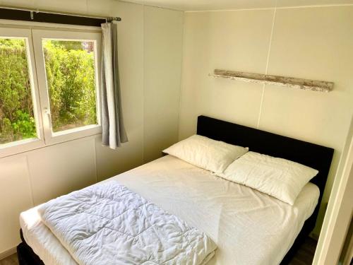 Mobilheim Zuidlaren في Tynaarlo: سرير في غرفة نوم مع نافذتين