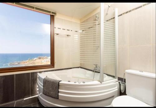 a bathroom with a tub and a toilet and a window at Mermaid Villa in Pomos