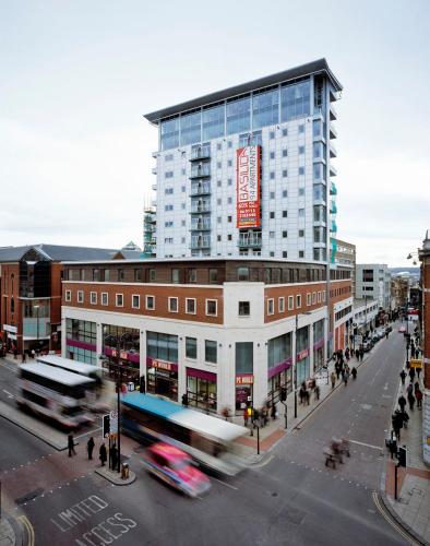 a tall building on a city street with a bus at Winners of 2025 traveller Award, Elegant two bedroom city central apartment with Netflix & WiFi in Leeds