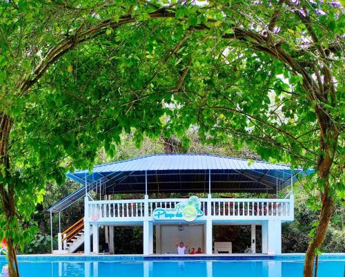 un pavillon blanc avec un toit bleu à côté d'une piscine dans l'établissement HOTEL RANCHO PLAYA DEL SOL, à Pedernales