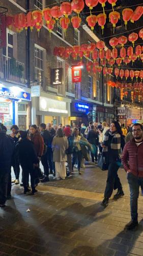 a crowd of people walking down a street at night at Little wooden Hut in London