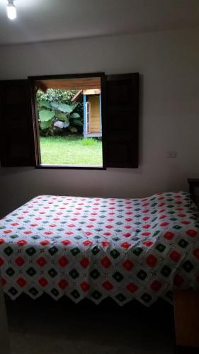 a bedroom with a bed with a red and white quilt at Chalet De Chalo in Jardin