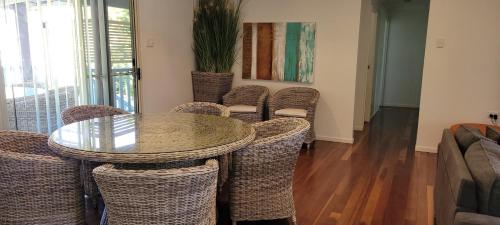 a dining room with a glass table and wicker chairs at Cabbage Palm Holiday Home in Agnes Water