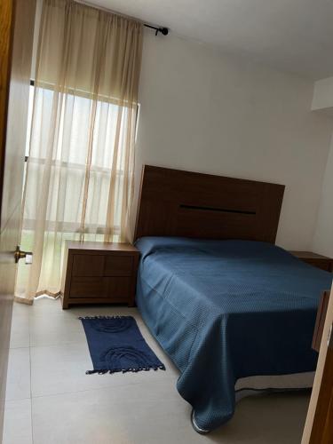 Un dormitorio con una cama azul y una ventana en Nohemani Suite, en Monterrey