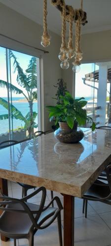 - une table à manger avec une plante en pot dans l'établissement Cantinho do paraíso da Deuza, à São Pedro da Aldeia
