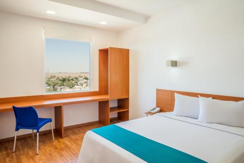 a bedroom with a bed and a desk and a window at One Mexicali in Mexicali