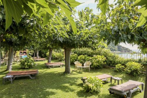 a park with benches and tables and trees at Rigat Park & Spa Hotel - Adults Recommended in Lloret de Mar