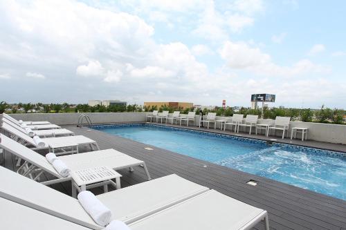 a pool on the roof of a building with white lounge chairs at Fiesta Inn Merida in Mérida