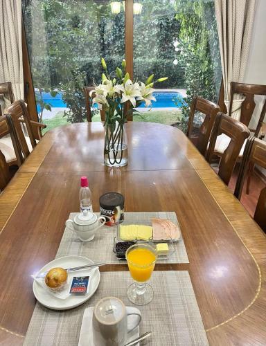 een tafel met een vaas met bloemen en een vaas met sinaasappelsap bij Habitación Matrimonial con baño privado in Santiago