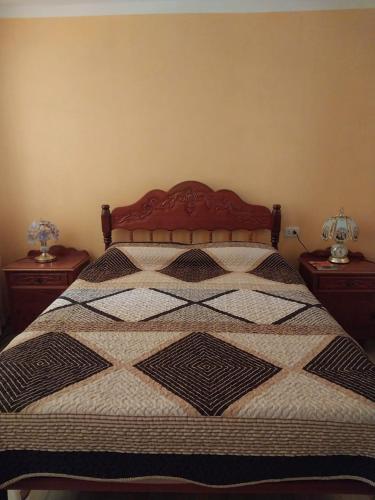 a bed with a quilt on it with two tables at DEPA CENTRICO CARAZ in Caraz