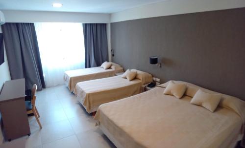 um quarto de hotel com três camas e uma janela em Hotel Alvarado Suites em Salta