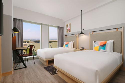 um quarto de hotel com duas camas e uma secretária em Moxy Putrajaya em Putrajaya