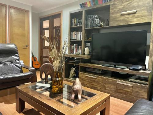 a living room with a television and a coffee table at Habitación Matrimonial con baño privado in Santiago