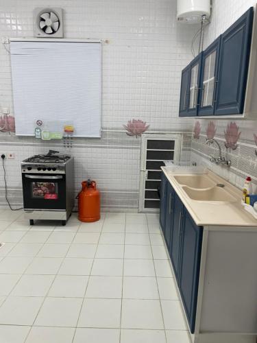 a kitchen with blue cabinets and a sink and a stove at همس المدينة شقة مفروشة in Abyār ‘Alī