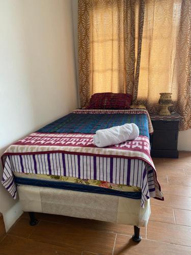 ein Bett mit einer gestreiften Decke darüber in der Unterkunft “Posada Vicentas” compartir con una familia Tz’utujil in San Juan La Laguna