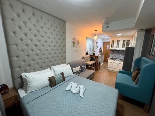 ein Schlafzimmer mit einem Bett und einem blauen Stuhl sowie ein Wohnzimmer in der Unterkunft CozyVilla at Pine Suites Tagaytay 2BR or Studio with FREE PARKING in Tagaytay