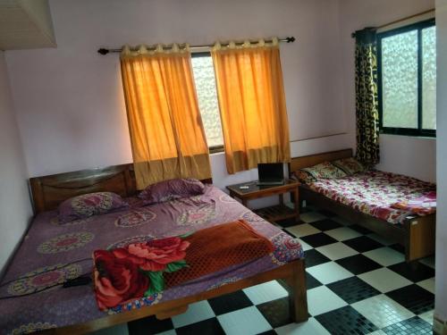 een slaapkamer met 2 bedden en een geruite vloer bij Advait Holiday Home in Nagaon