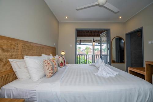 1 dormitorio con 1 cama blanca grande con almohadas blancas en The Peacock Inn en Ubud