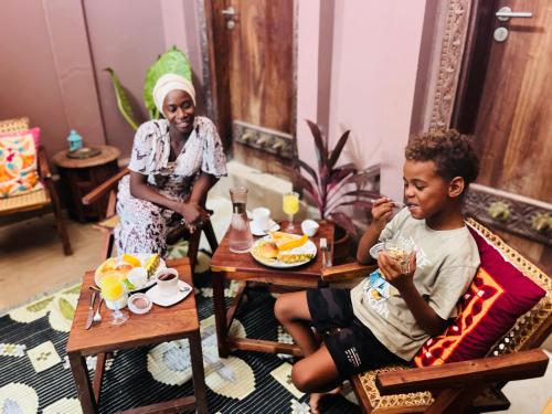 a woman and a boy sitting at a table eating food at Binta Boutique Hotel in Nungwi