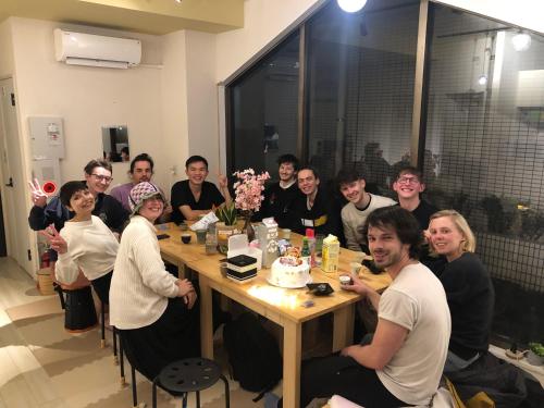 un grupo de personas sentadas alrededor de una mesa con un pastel en MAKOTO GUESTHOUSE -Enjoy your stay-, en Tokio