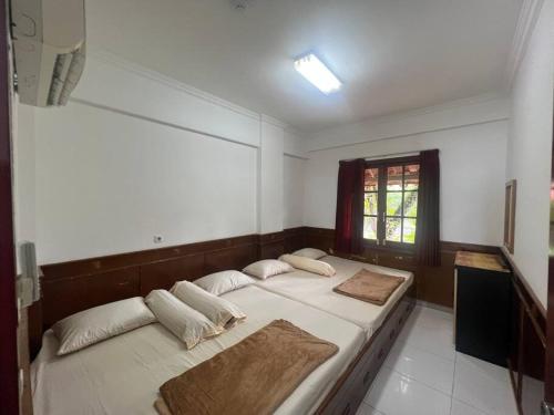 Un dormitorio con dos camas con almohadas y una ventana. en Apartemen carita Anyer view laut, en Carita