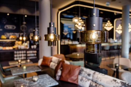 a restaurant with tables and chairs and lights at Motel One Nürnberg-City in Nuremberg