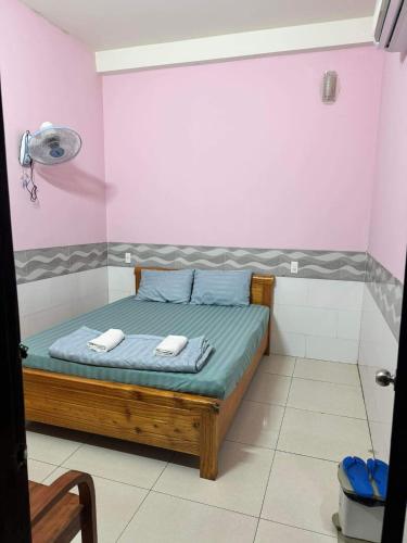 een slaapkamer met een bed in een roze kamer bij Nhà nghỉ Hà Anh in Thuan An